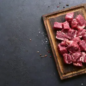 Diced raw meat on a wooden board.