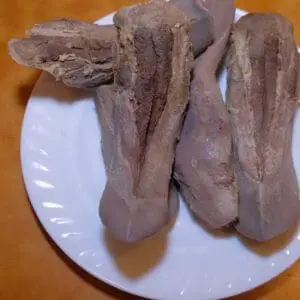 Cooked beef tongues on a white plate.