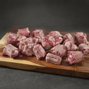 Raw meat pieces on wooden cutting board.