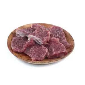 Raw beef slices on a wooden plate.