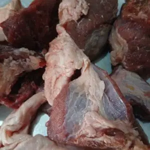 Raw beef chunks on a metal surface.